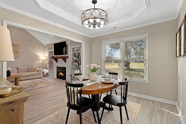 dining area featuring visible vents, a notable chandelier, a fireplace, and light wood finished floors