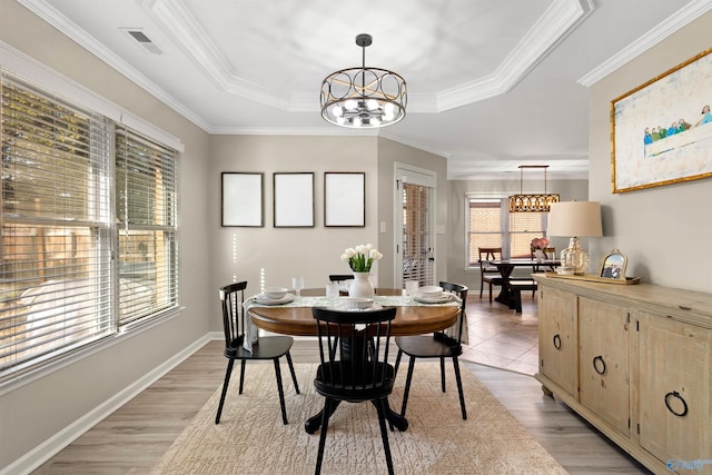 dining area with an inviting chandelier, visible vents, a tray ceiling, and ornamental molding