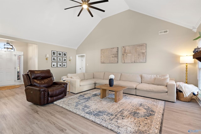 living room with visible vents, crown molding, light wood-style flooring, high vaulted ceiling, and a ceiling fan