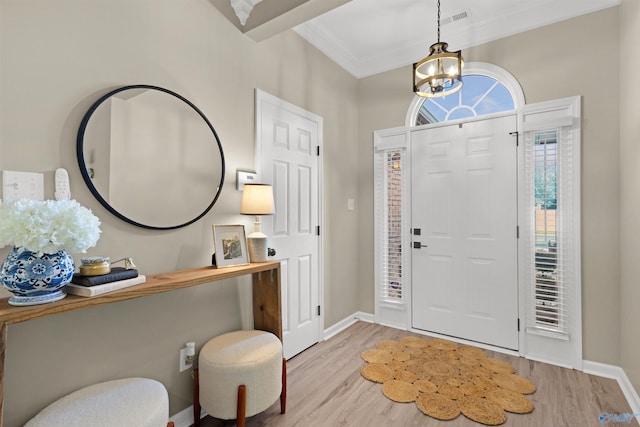 foyer featuring ornamental molding, baseboards, an inviting chandelier, and wood finished floors