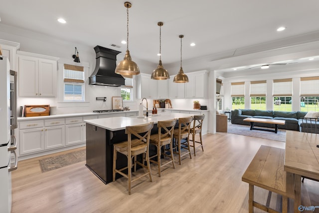 313 Merrydale Dr, Huntsville, AL 35811 - kitchen with premium range hood, a center island with sink, light countertops, a breakfast bar area, and gas cooktop