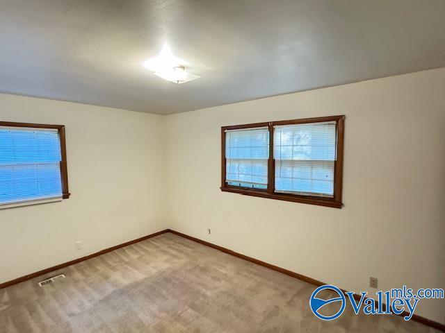 carpeted spare room featuring visible vents and baseboards