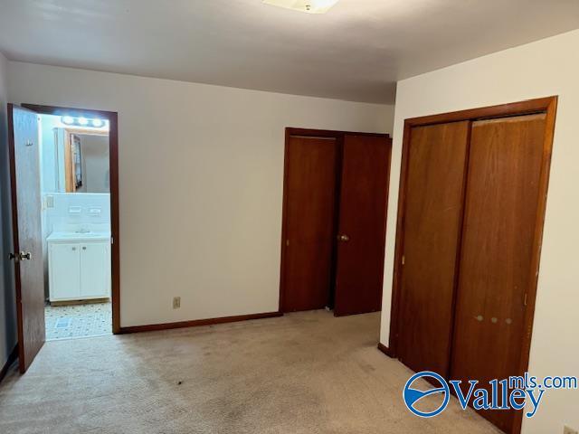 unfurnished bedroom with baseboards, connected bathroom, and light colored carpet