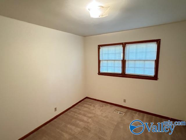 unfurnished room featuring carpet flooring, visible vents, and baseboards