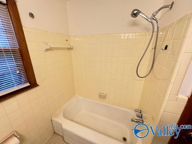 bathroom with washtub / shower combination and tile walls