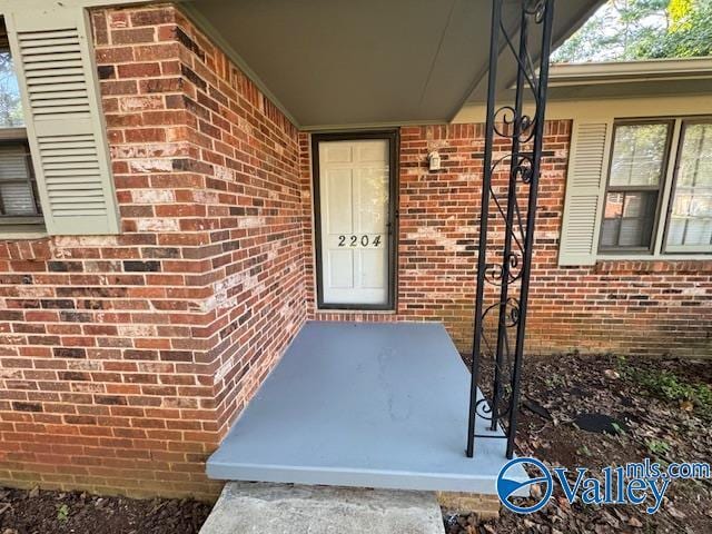 doorway to property featuring brick siding