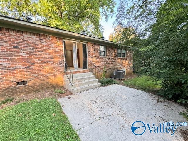 exterior space with a patio area, crawl space, brick siding, and central air condition unit