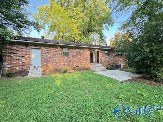 back of property with entry steps, a lawn, and brick siding