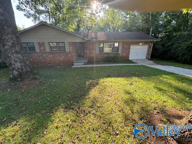 ranch-style home with an attached garage, a front lawn, concrete driveway, and brick siding