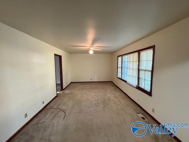 unfurnished room with light carpet, baseboards, visible vents, and a ceiling fan