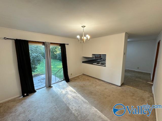 unfurnished room with baseboards, an inviting chandelier, and light colored carpet