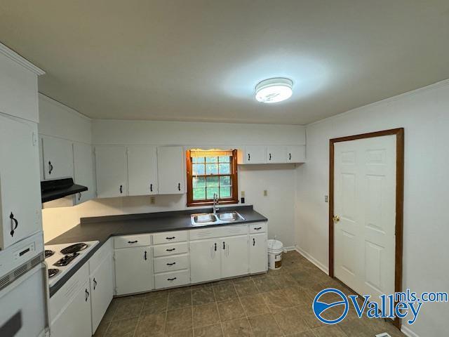 kitchen featuring dark countertops, white cabinetry, a sink, white appliances, and exhaust hood