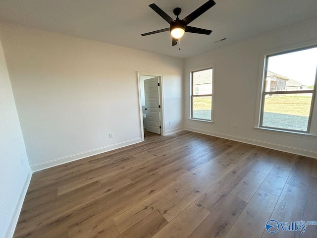 spare room featuring baseboards, hardwood / wood-style flooring, visible vents, and ceiling fan