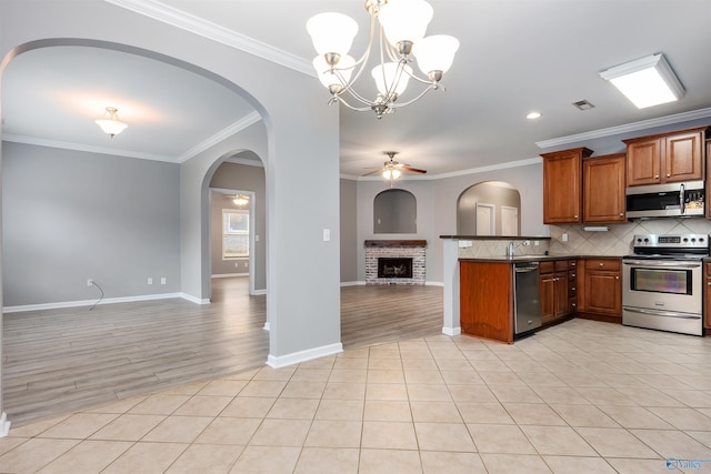 kitchen with light tile patterned flooring, pendant lighting, backsplash, ornamental molding, and stainless steel appliances