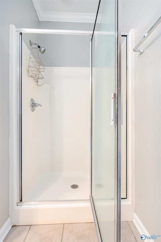 bathroom with ornamental molding, a shower with shower door, and tile patterned floors