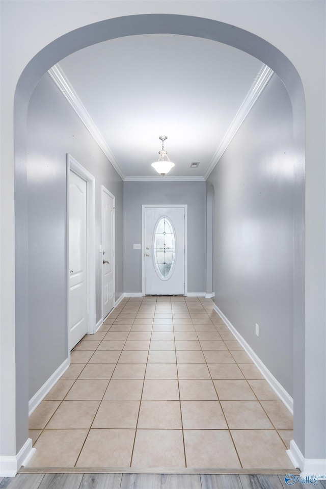 doorway to outside with light tile patterned floors and ornamental molding