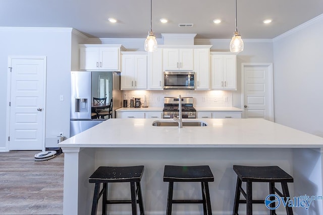 kitchen featuring a center island with sink, white cabinetry, stainless steel appliances, and light hardwood / wood-style flooring