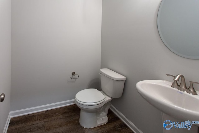 bathroom featuring wood-type flooring, toilet, and sink