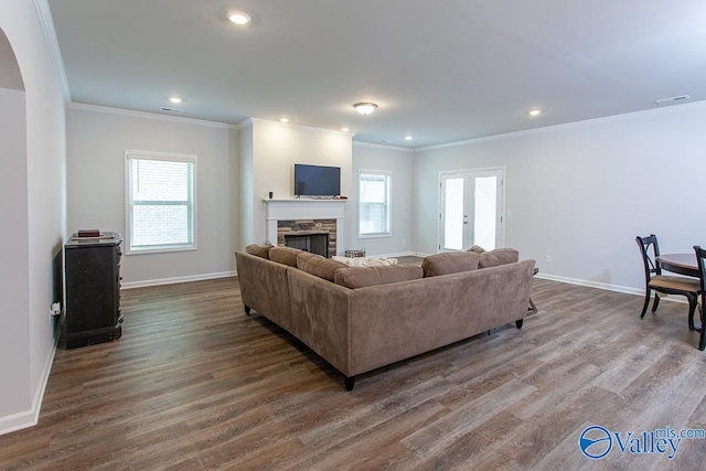 living room featuring a stone fireplace, a wealth of natural light, hardwood / wood-style floors, and crown molding