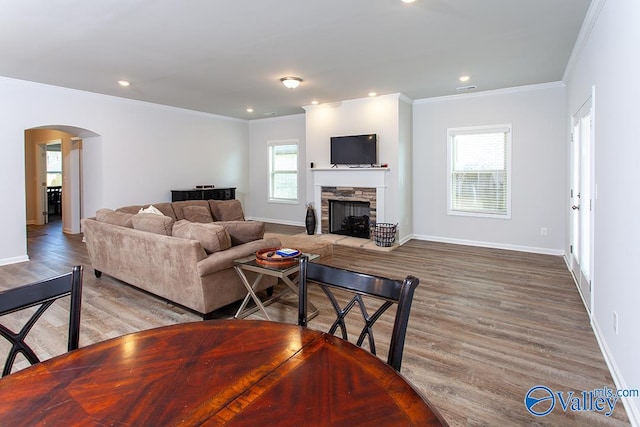 living room with a wealth of natural light, a fireplace, ornamental molding, and hardwood / wood-style flooring