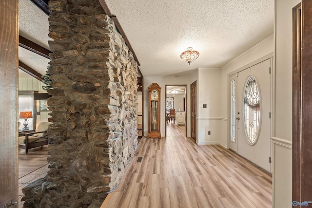 entryway featuring crown molding, light hardwood / wood-style flooring, beamed ceiling, and a textured ceiling