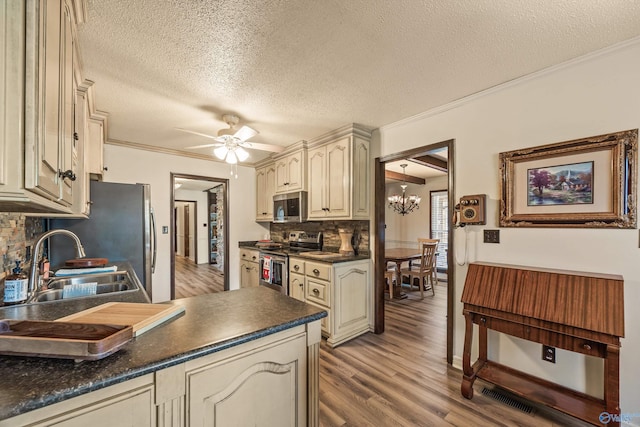 kitchen featuring cream cabinets, sink, decorative backsplash, a textured ceiling, and appliances with stainless steel finishes