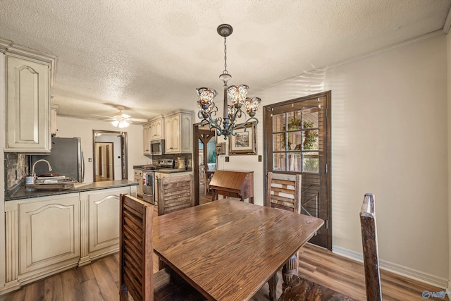 dining space featuring sink, dark hardwood / wood-style flooring, crown molding, a textured ceiling, and ceiling fan with notable chandelier