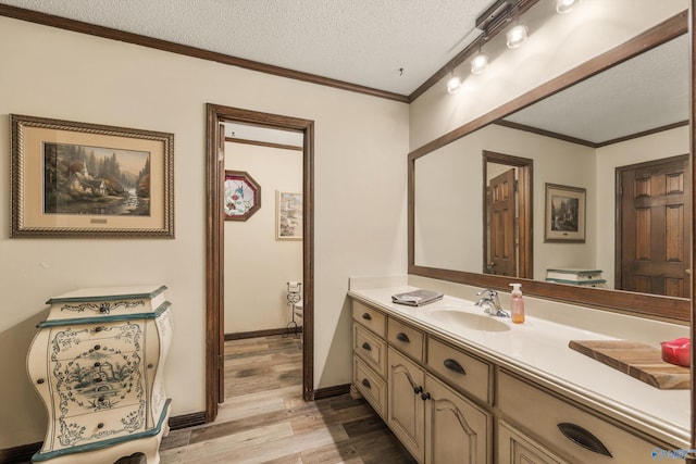 bathroom with crown molding, vanity, a textured ceiling, and hardwood / wood-style flooring