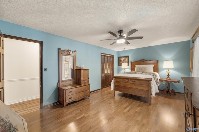 bedroom with ceiling fan, light wood-type flooring, a textured ceiling, and a closet