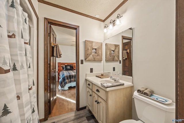 bathroom featuring ornamental molding, vanity, a textured ceiling, hardwood / wood-style floors, and toilet