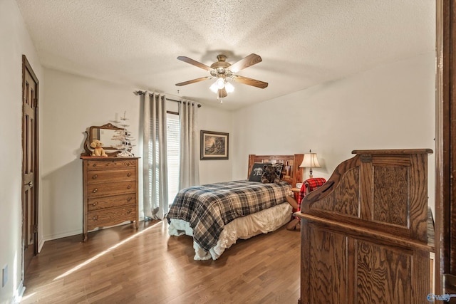 bedroom with ceiling fan, wood-type flooring, and a textured ceiling