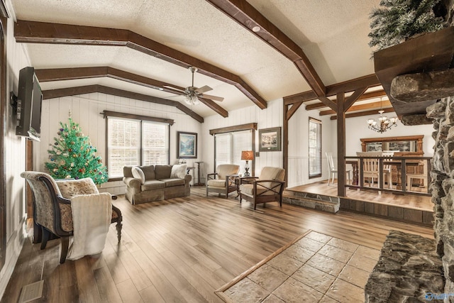 living room with ceiling fan with notable chandelier, hardwood / wood-style floors, and a textured ceiling