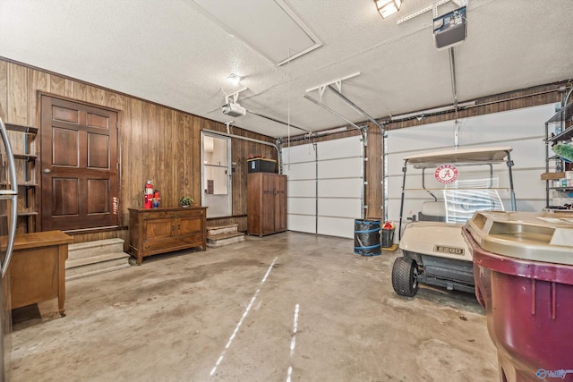 garage with wood walls and a garage door opener