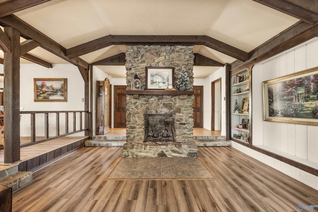 unfurnished living room with built in shelves, a fireplace, vaulted ceiling, and hardwood / wood-style flooring