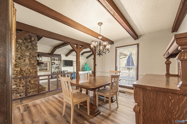 dining space featuring beam ceiling, light hardwood / wood-style floors, a textured ceiling, and a notable chandelier