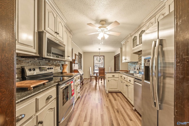 kitchen featuring tasteful backsplash, stainless steel appliances, sink, pendant lighting, and cream cabinetry