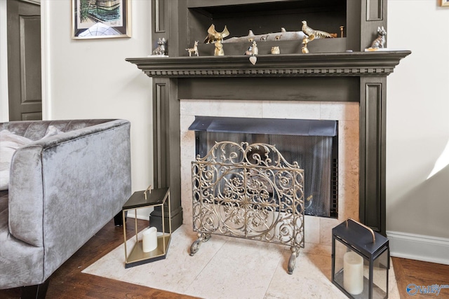 interior details with wood-type flooring and a tile fireplace