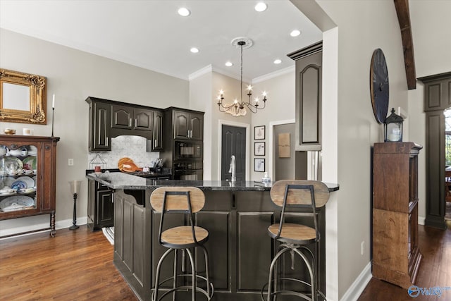 kitchen featuring black appliances, a kitchen bar, dark stone countertops, an inviting chandelier, and dark hardwood / wood-style floors