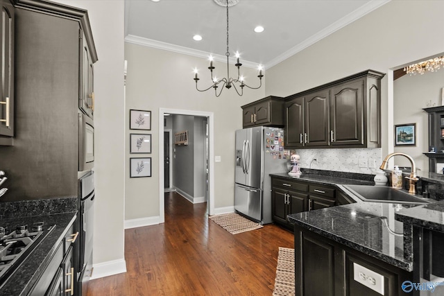 kitchen featuring appliances with stainless steel finishes, sink, pendant lighting, ornamental molding, and dark hardwood / wood-style floors