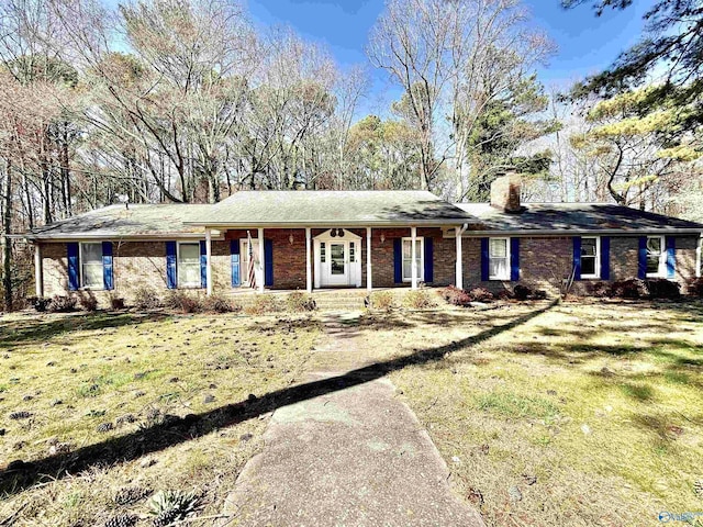 ranch-style house featuring covered porch, a chimney, and a front yard