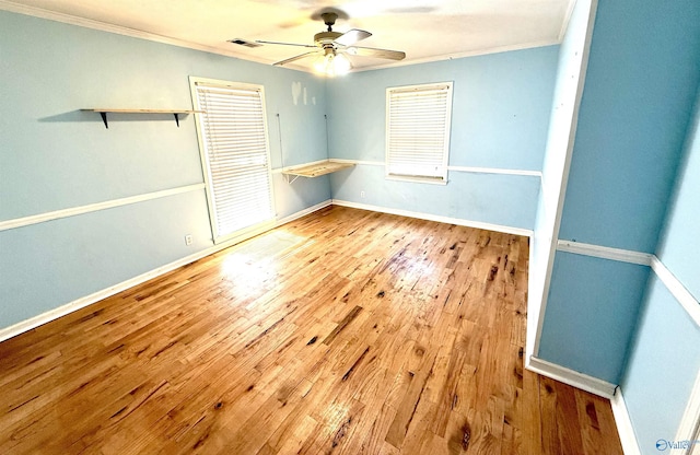 unfurnished room with a ceiling fan, visible vents, wood-type flooring, and ornamental molding