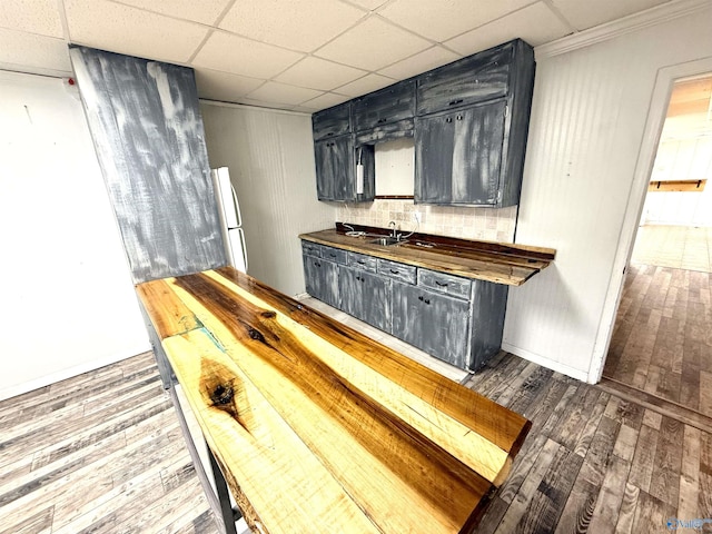 kitchen featuring a sink, dark countertops, wood finished floors, freestanding refrigerator, and a paneled ceiling