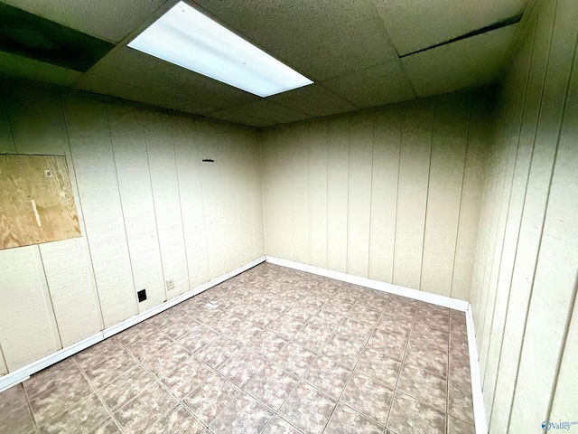 below grade area with a drop ceiling and wood walls