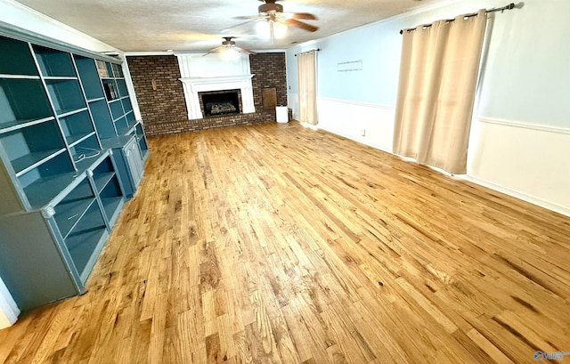 unfurnished living room with wood finished floors, a brick fireplace, a ceiling fan, and a textured ceiling