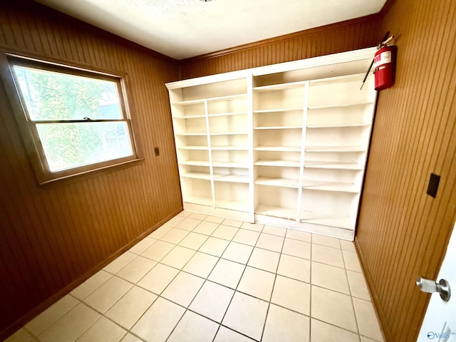 interior space featuring wooden walls, light tile patterned floors, and baseboards