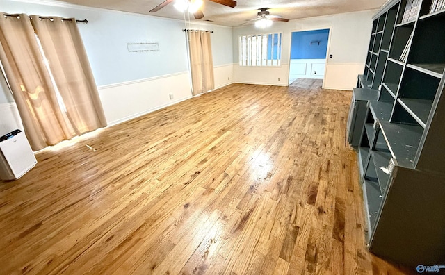 interior space with wood finished floors, wainscoting, and a ceiling fan