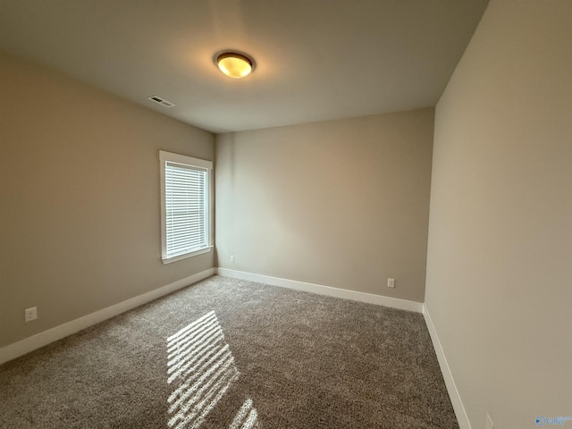 carpeted spare room featuring visible vents and baseboards