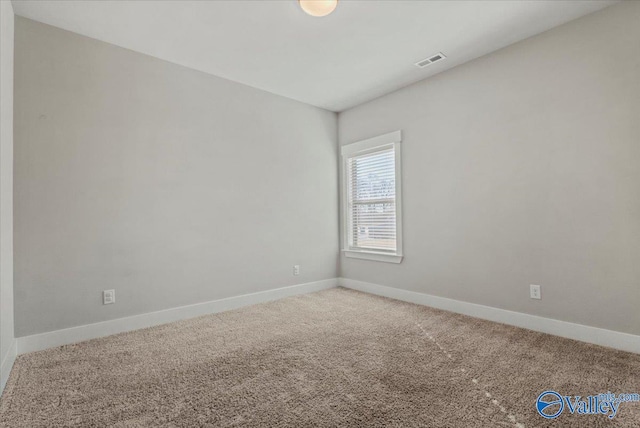 unfurnished room with carpet, visible vents, and baseboards