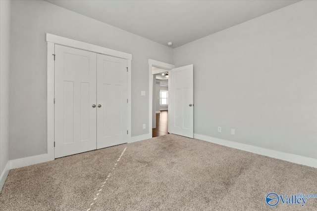 unfurnished bedroom with a closet, carpet flooring, and baseboards