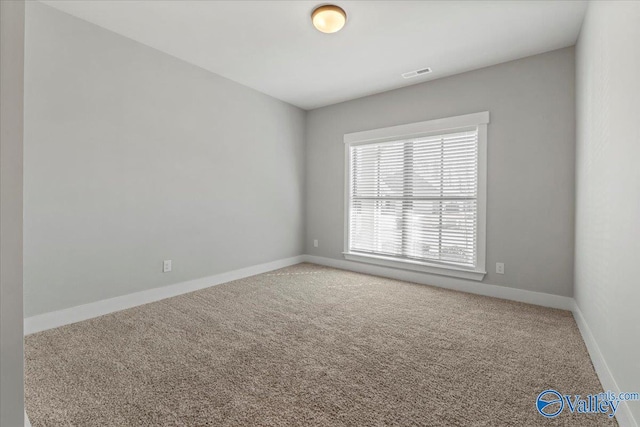 spare room featuring carpet, visible vents, and baseboards